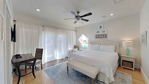 A modern bedroom with a large bed, a desk, a chair, a ceiling fan, and a window with curtains. - Aloha Sandy Bay by Southern Vacation Rentals (Santa Rosa Beach)