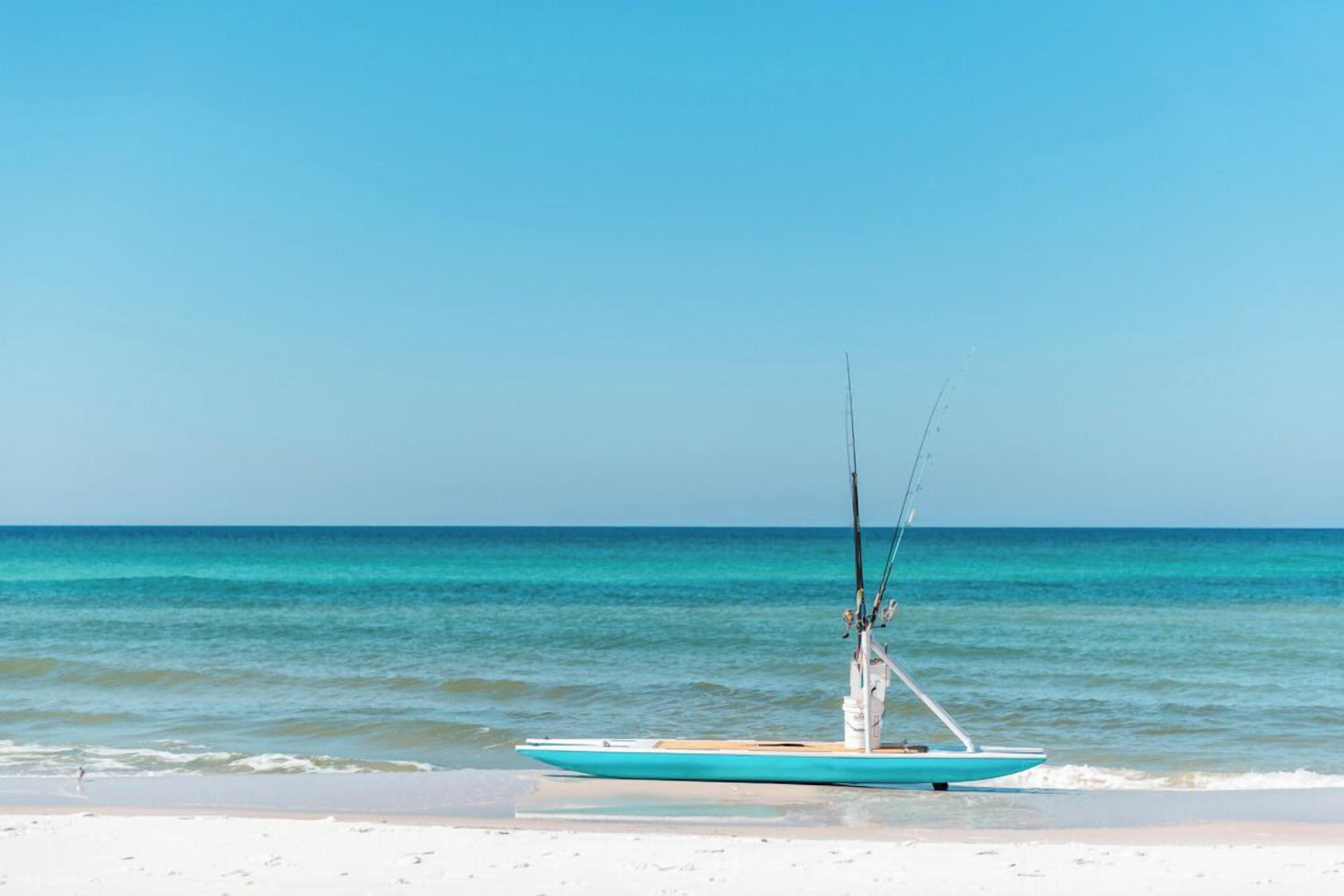 A boat on a beach with calm waters and a clear sky.