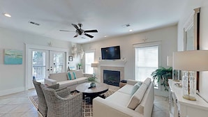 A spacious living room with a fireplace, comfortable seating, and a ceiling fan. - Aloha Sandy Bay by Southern Vacation Rentals (Santa Rosa Beach)