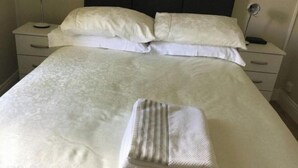 A neatly made bed with white linens and a folded towel, a dark headboard, and bedside tables with lamps. - distance 2 minutes Adare Village  Manor, Hotels, Restaurant’s, Pubs, Golf Course (Adare)