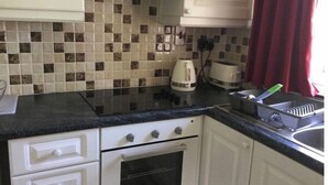 A kitchen with white cabinets, a black countertop, a tiled backsplash, a kettle, a toaster, and a sink. - distance 2 minutes Adare Village  Manor, Hotels, Restaurant’s, Pubs, Golf Course (Adare)