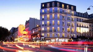 A multi-story hotel with balconies, illuminated windows, and a street view with light trails. - Manolita Paris (Paris)