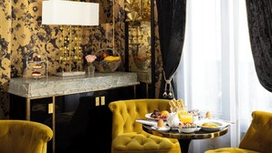 A dining area with a round table set for breakfast, yellow chairs, and a decorative wall with a floral pattern. - Manolita Paris (Paris)