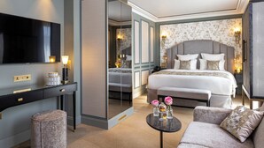 A hotel room with a large bed, a TV, a desk, and a sofa. - Manolita Paris (Paris)