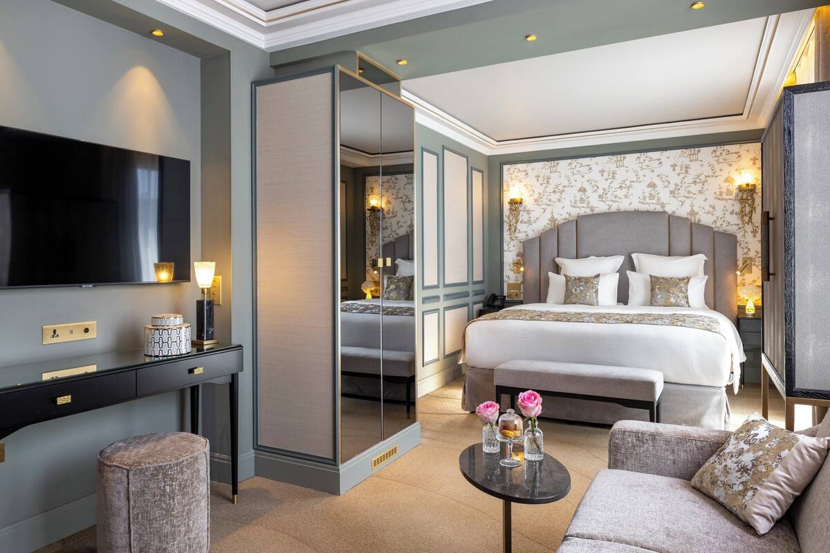 A hotel room with a large bed, a TV, a desk, and a sofa.