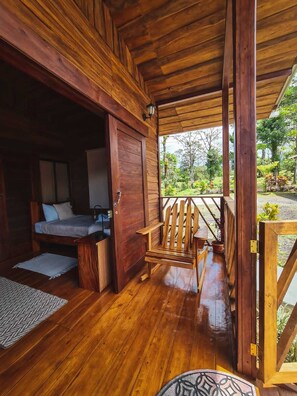 A wooden cabin with a bed, a wooden chair, and a small table.