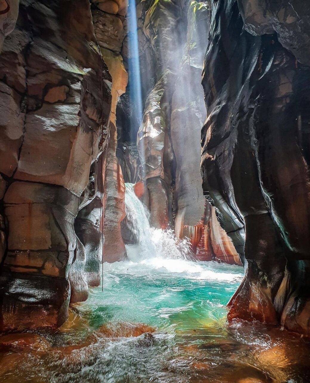 Une formation rocheuse naturelle avec une cascade et un bassin d’eau.