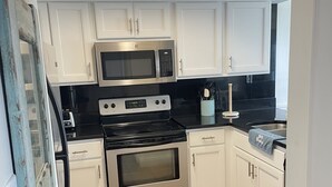 A kitchen with white cabinets, a stainless steel microwave, a stove, and a sink. - 3 Bedroom, Gulf View, Orange Beach Condo--A Boardwalk to Salt Life (Orange Beach)