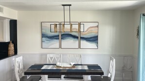 A dining area with a table and chairs, a wall-mounted artwork, and a ceiling light fixture. - 3 Bedroom, Gulf View, Orange Beach Condo--A Boardwalk to Salt Life (Orange Beach)