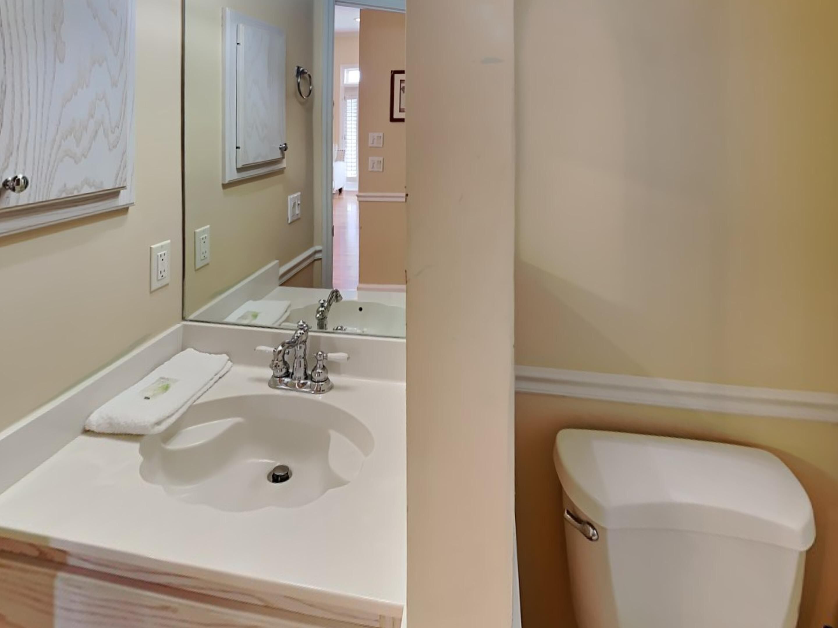 A bathroom with a white sink, a mirror, and a toilet.
