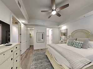 Une chambre à coucher avec un lit, une table de chevet, une lampe et un ventilateur de plafond.