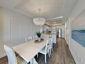 Une cuisine moderne avec des meubles blancs, des appareils en acier inoxydable et un îlot central.