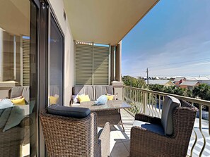 A balcony with wicker furniture, a glass door, and a view of houses in the background. - Abacos #304 by Southern Vacation Rentals (Santa Rosa Beach)