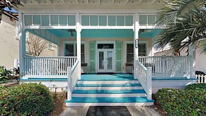 A two-story building with a porch, a sign indicating a garden center, and a number '112' on the wall. - A Garden Cottage by Southern Vacation Rentals (Miramar Beach)