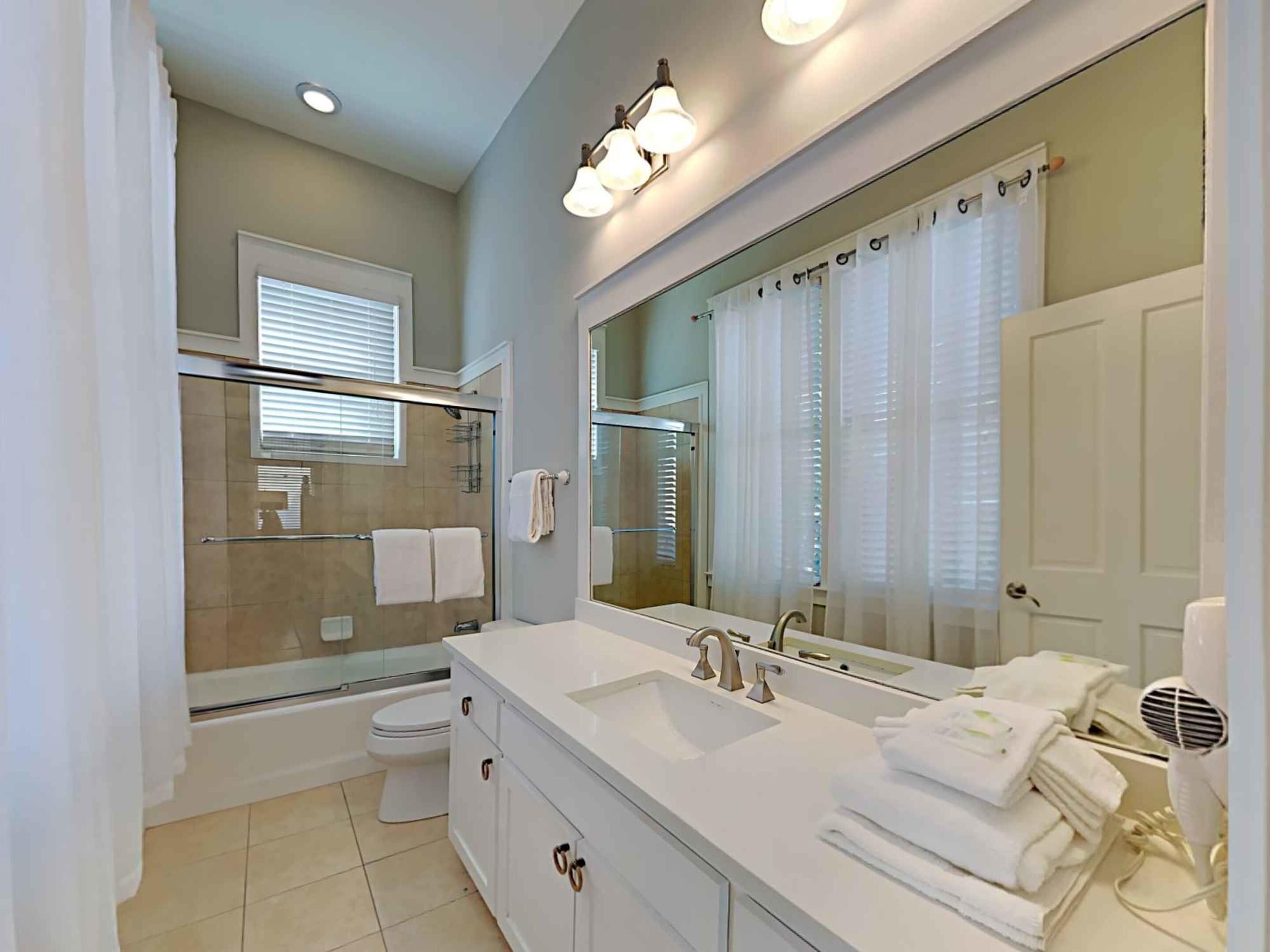 Une salle de bain moderne avec un grand miroir, une baignoire, une douche et des toilettes.