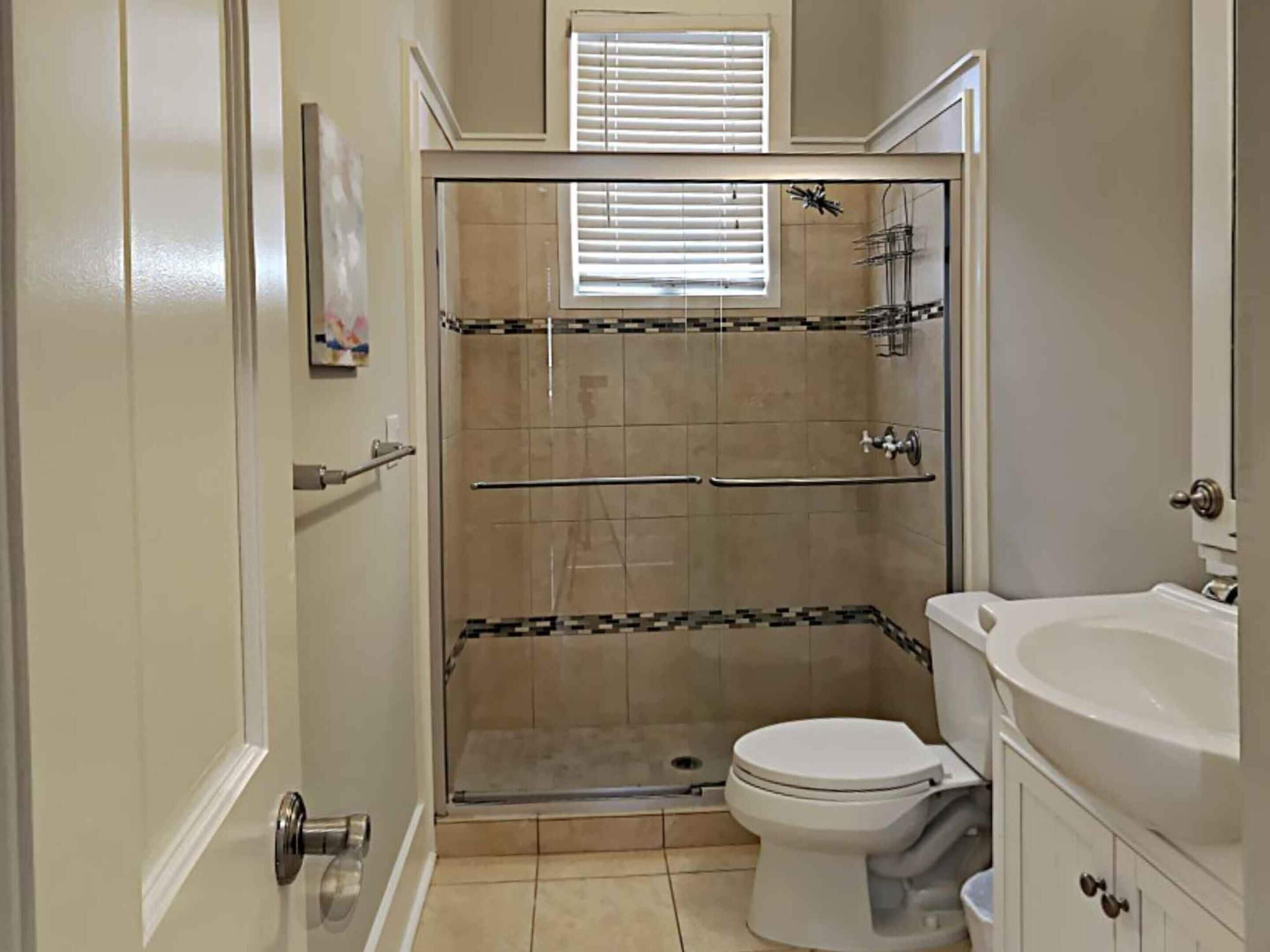 A bathroom with a shower, toilet, and sink.