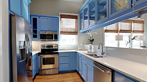 A modern kitchen with blue cabinets, stainless steel appliances, and a wooden floor. - A Garden Cottage by Southern Vacation Rentals (Miramar Beach)