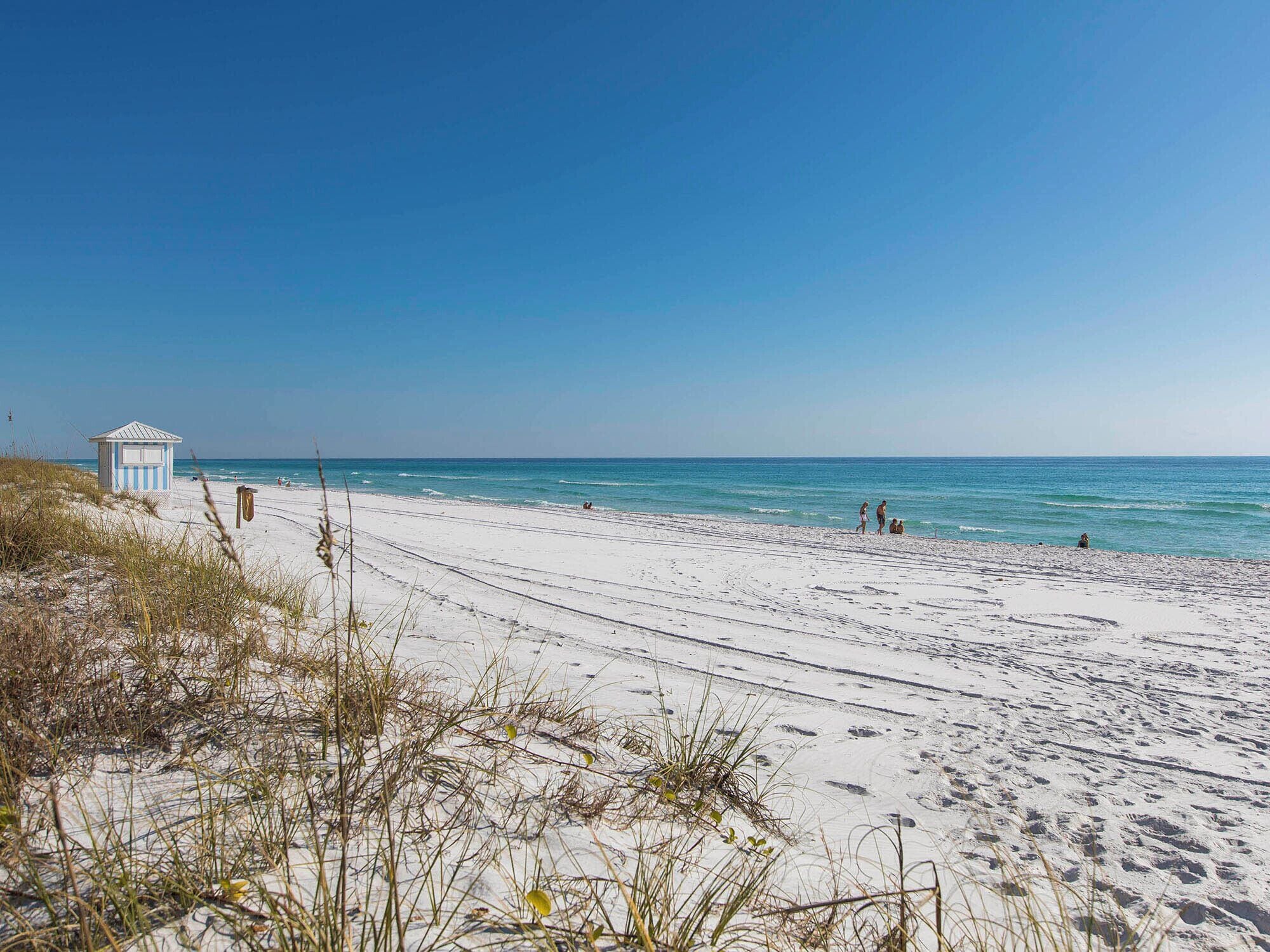A beach with a lifeguard tower, sandy shore, and clear blue sky.