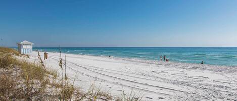 A beach with a lifeguard tower, sandy shore, and clear blue sky.