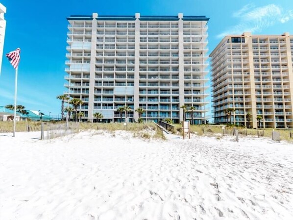 A multi-story hotel with a modern design, featuring a large number of balconies and a beach view.