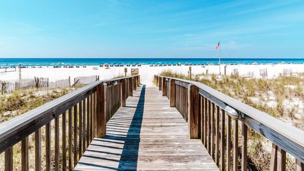 A wooden boardwalk leading to a beach with white sand and a clear blue sky. - Bluewater #403 by Southern Vacation Rentals (Orange Beach)