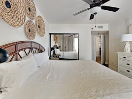 A hotel room with a large bed, a ceiling fan, a mirror, and a wardrobe.
