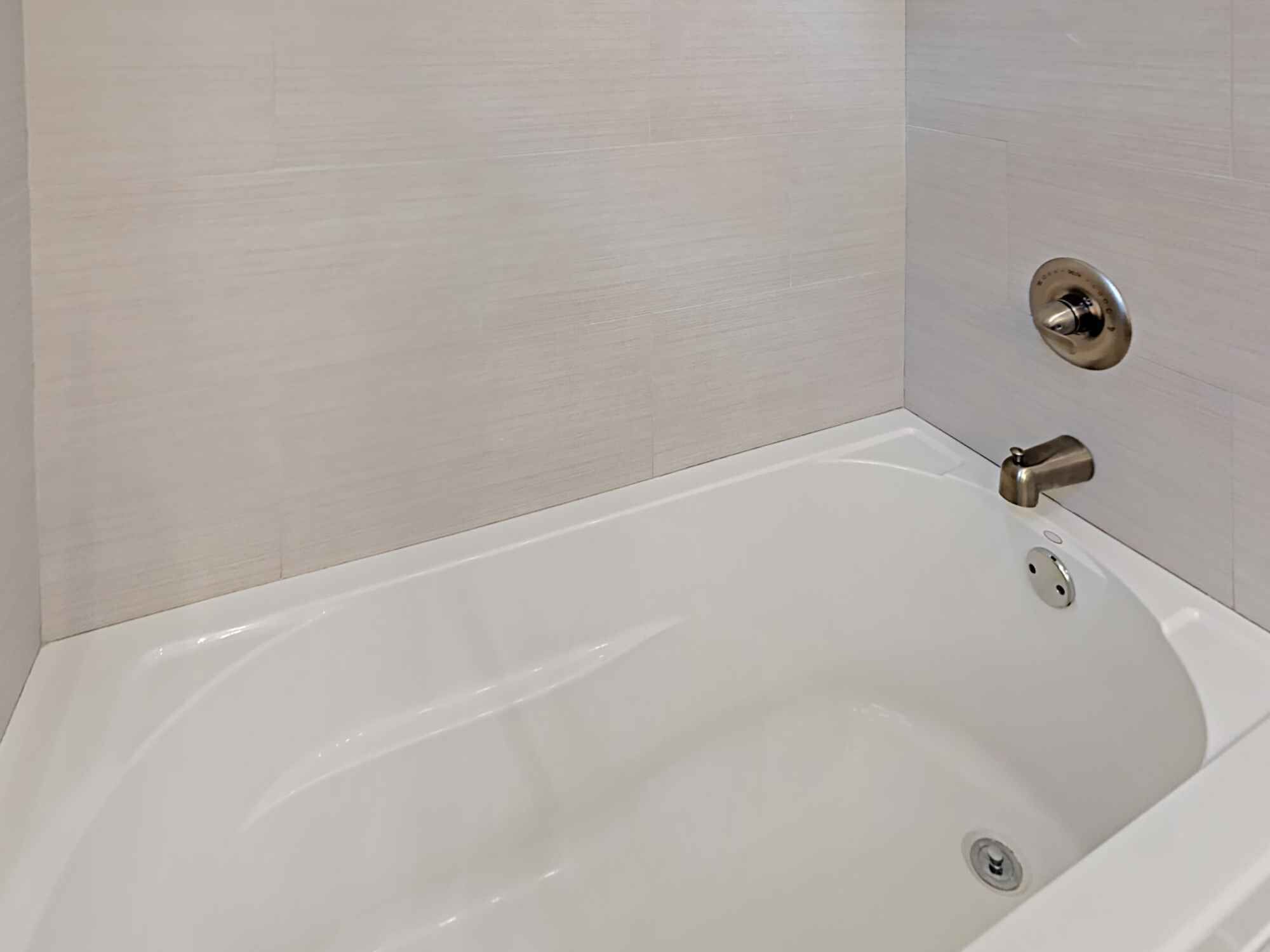 A white bathtub with a modern faucet and a drain plug.