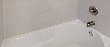 A white bathtub with a modern faucet and a drain plug.