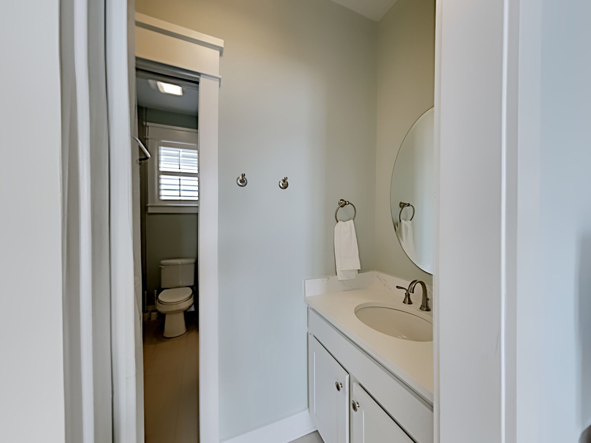 A bathroom with a toilet, sink, and mirror.