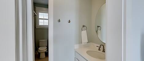 A bathroom with a toilet, sink, and mirror.