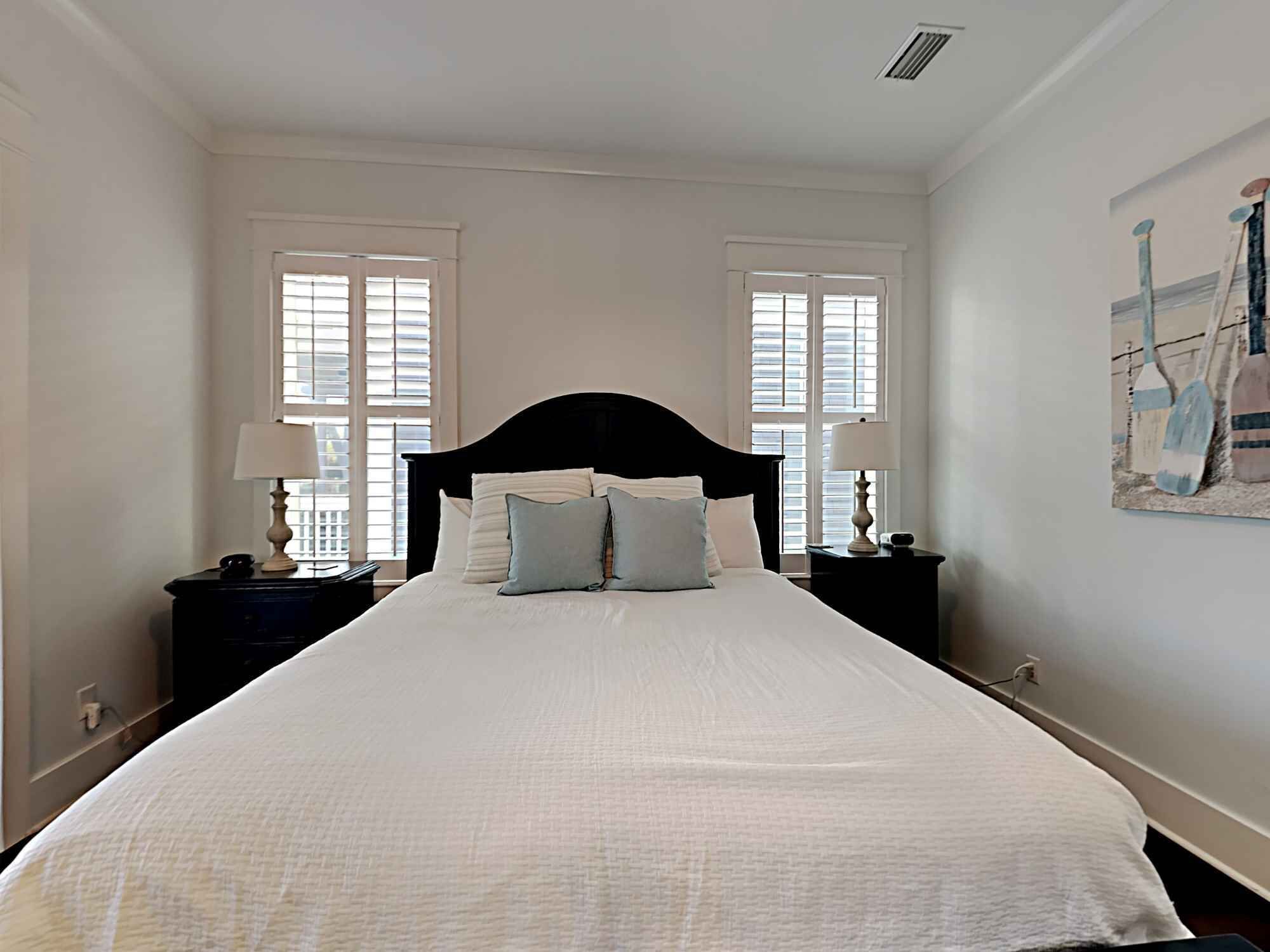 A hotel room with a large bed, two bedside tables with lamps, and a painting on the wall.