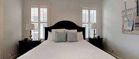 A hotel room with a large bed, two bedside tables with lamps, and a painting on the wall.