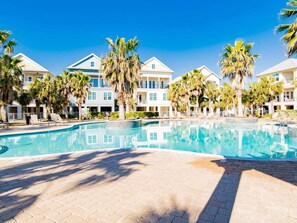 Een resort met een zwembad, palmbomen en meerlaagse gebouwen met balkons.