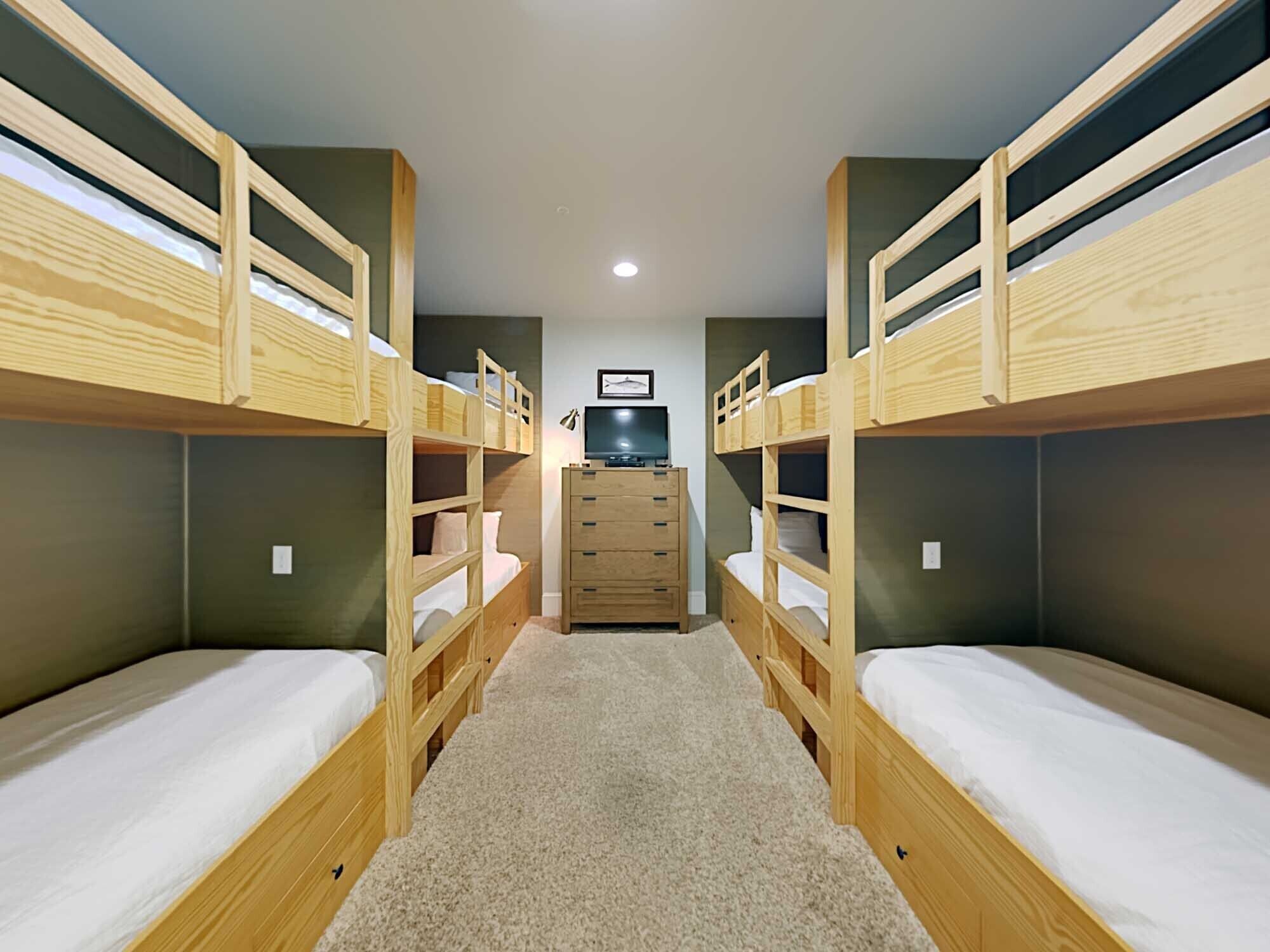 Une chambre avec des lits superposés, une commode et un téléviseur.