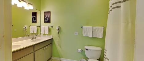 A bathroom with a green wall, a white sink, a toilet, and a shower curtain.
