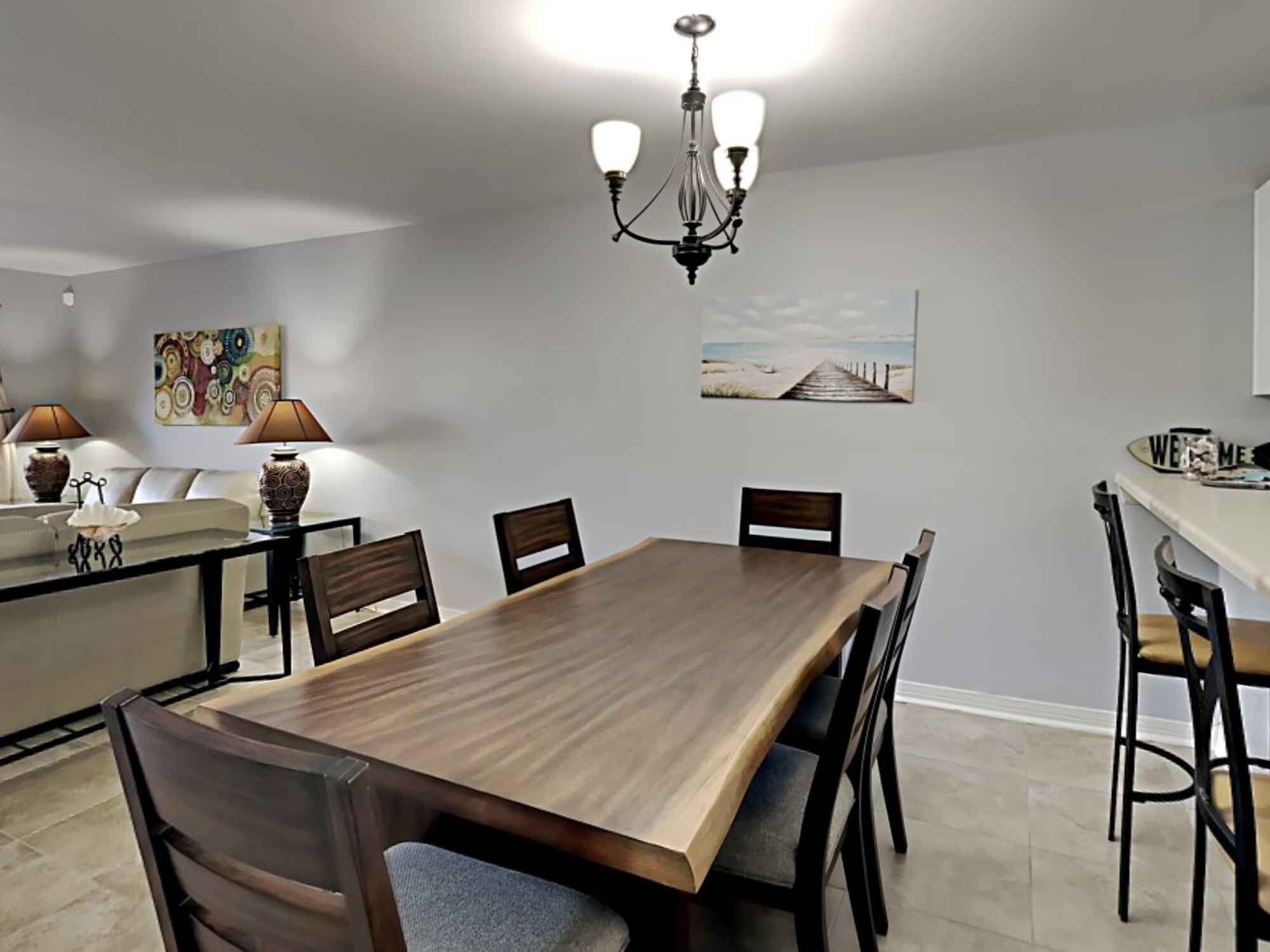A dining area with a wooden table, chairs, a chandelier, and artwork on the walls.