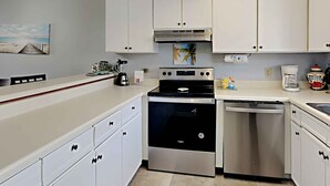 Une cuisine moderne avec des armoires blanches, une cuisinière en acier inoxydable et un lave-vaisselle.