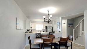 Une cuisine moderne avec des meubles blancs, un îlot central et un lustre.