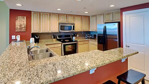 A kitchen with granite countertops, stainless steel appliances, and beige cabinetry. - Palazzo #1407 by Resort Collection (Panama City Beach)