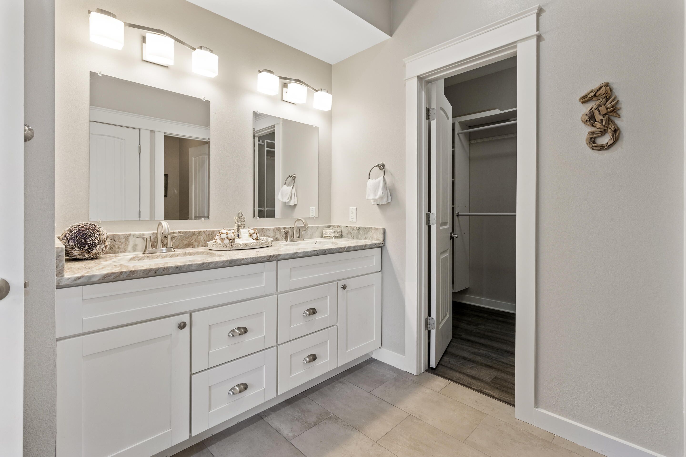 A modern bathroom with a large vanity, a walk-in closet, and a mirror with lights.