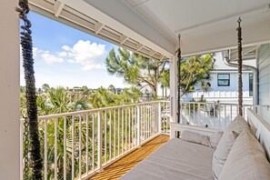 A balcony with a wooden floor, white railing, and a cushioned seating area.