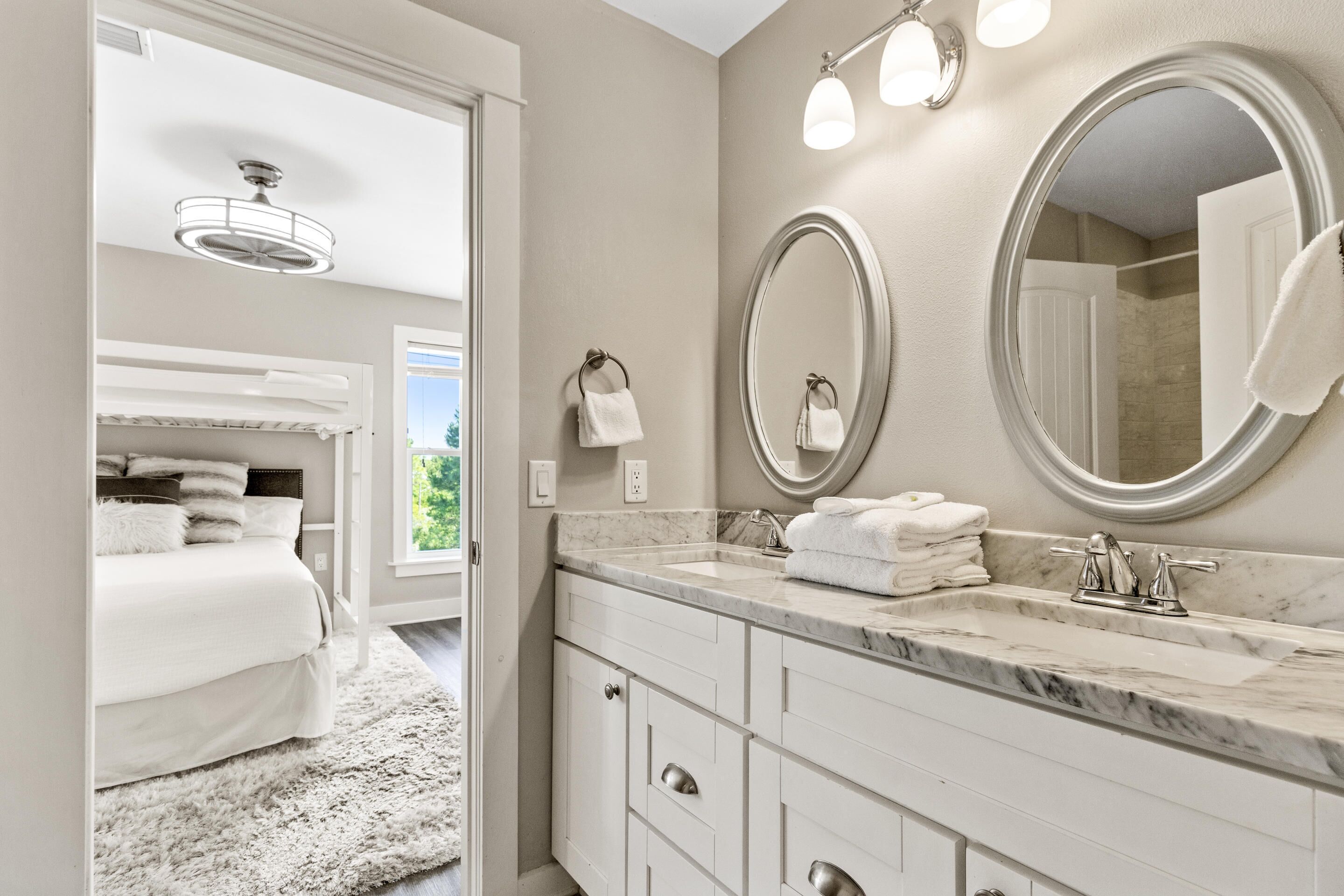 A modern bathroom with a marble sink, two mirrors, and a large window.