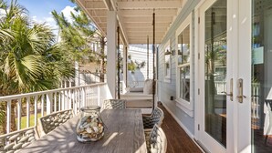 A covered outdoor seating area with a table, chairs, and a glass vase with stones. - Easy Breezy by Southern Vacation Rentals (Santa Rosa Beach)