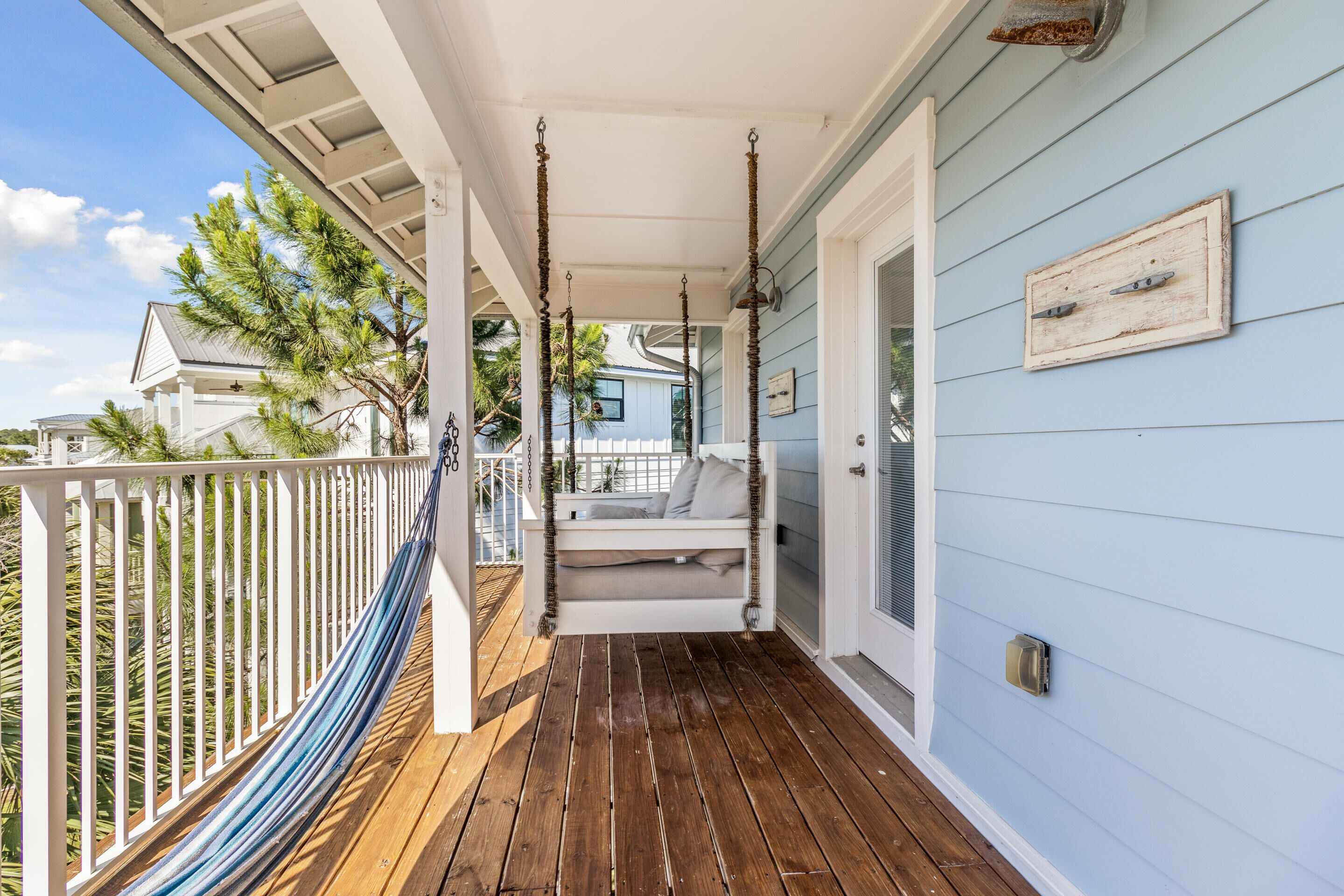 A porch with a hammock, a white bench, and a door.