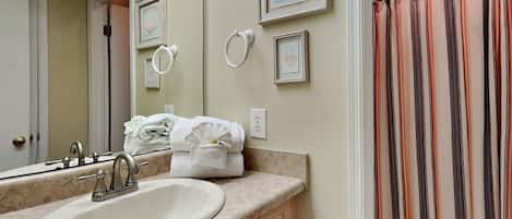 A bathroom with a sink, mirror, towel rack, and striped shower curtain.