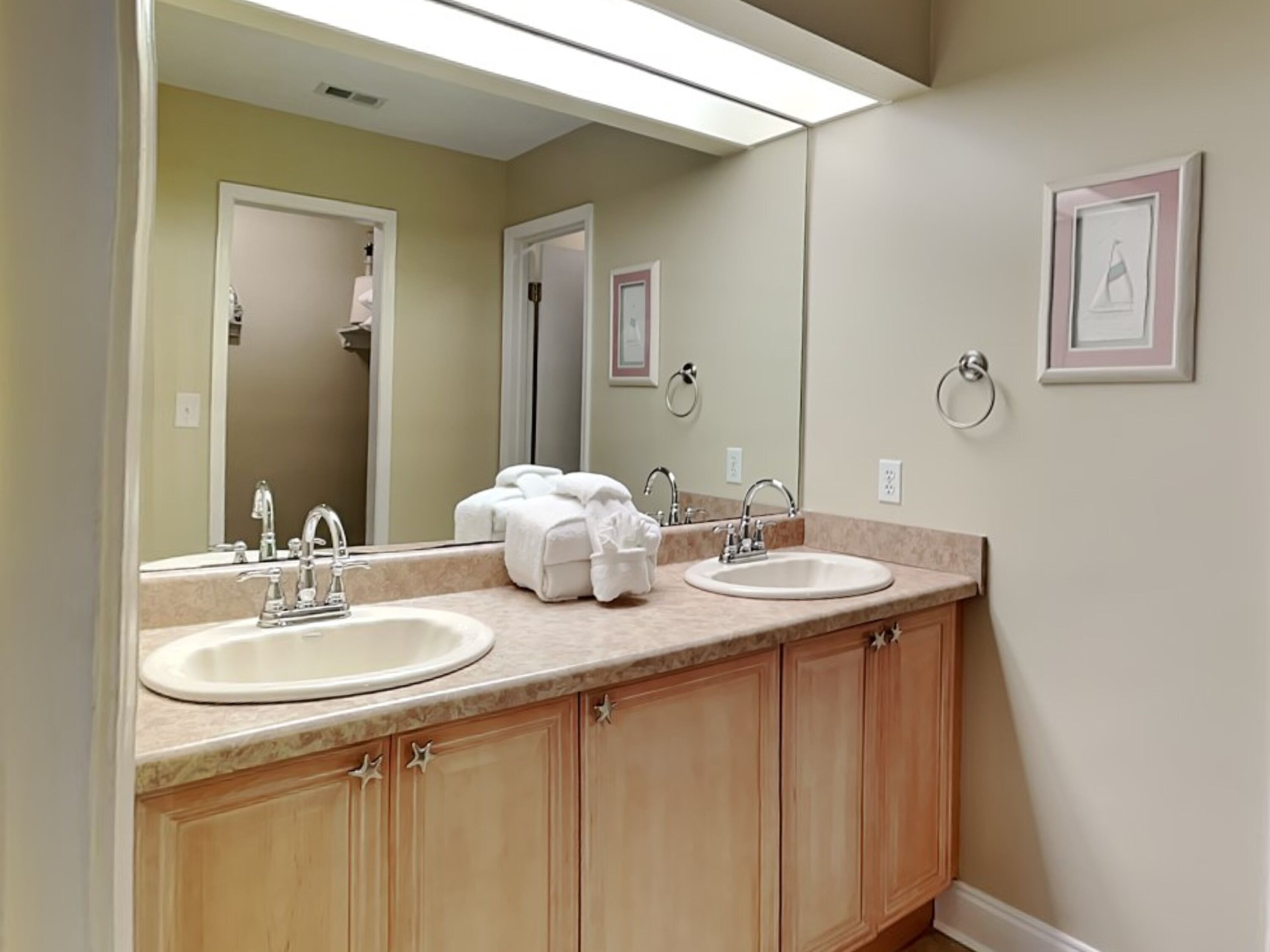 Une salle de bain avec deux lavabos, un miroir et des meubles en bois.