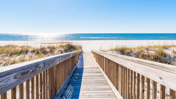 A wooden boardwalk leading to a beach with clear skies and calm waters. - Spinnaker #2A by Southern Vacation Rentals (Pensacola)