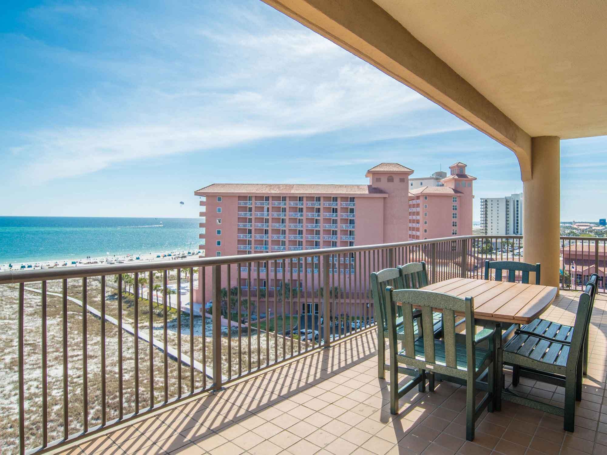 A balcony with a view of the beach and a hotel building.
