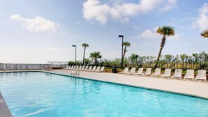 Ein Swimmingpool mit Liegestühlen und Palmen.