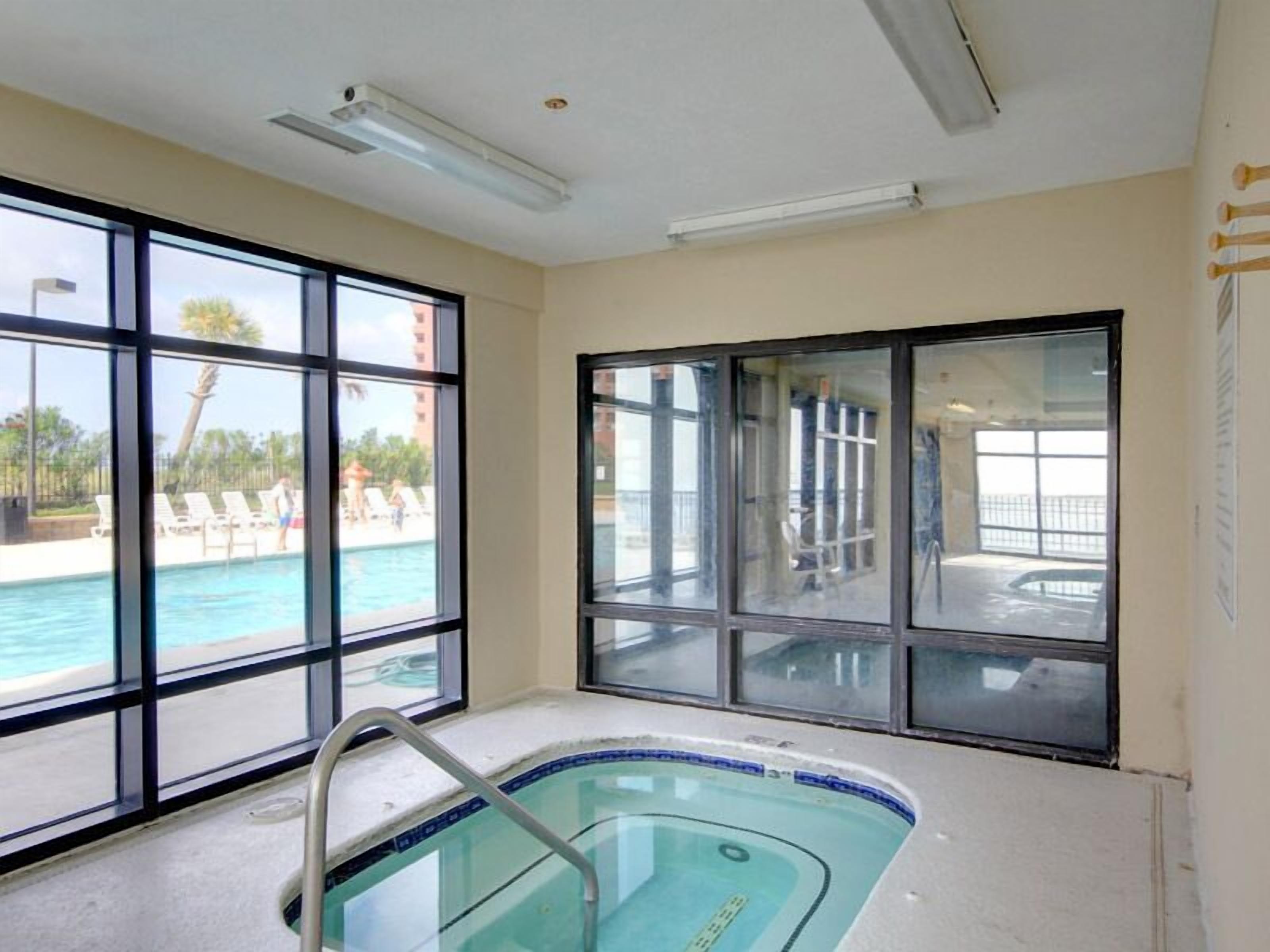 A swimming pool area with a view of a poolside and a building in the background.